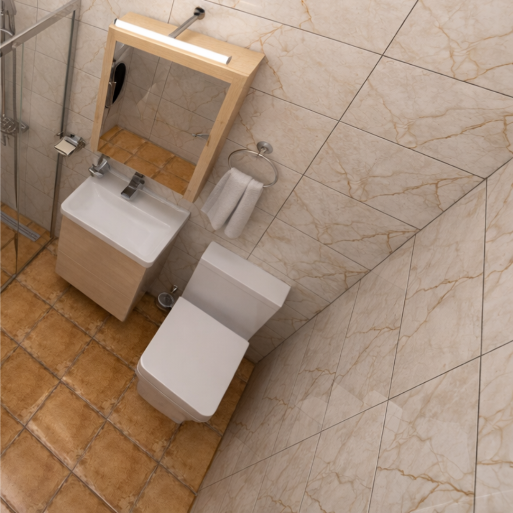 Compact bathroom with a white toilet and a small vanity sink under a wooden-framed mirror, beige tiled walls and floor, towel ring nearby.
