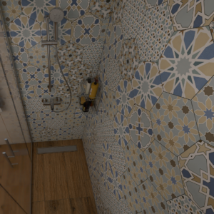 Shower alcove with blue, beige, and gray patterned tile walls, a handheld showerhead, and a metal caddy holding shampoo bottles.